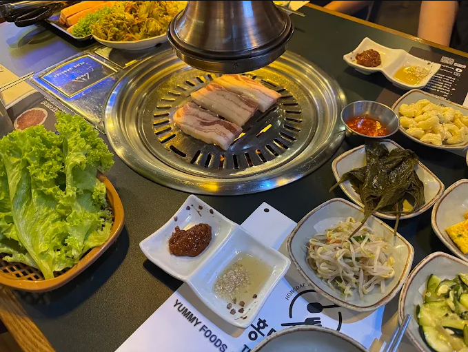 Pork belly grilling at a Hongdae Korean BBQ table with banchan